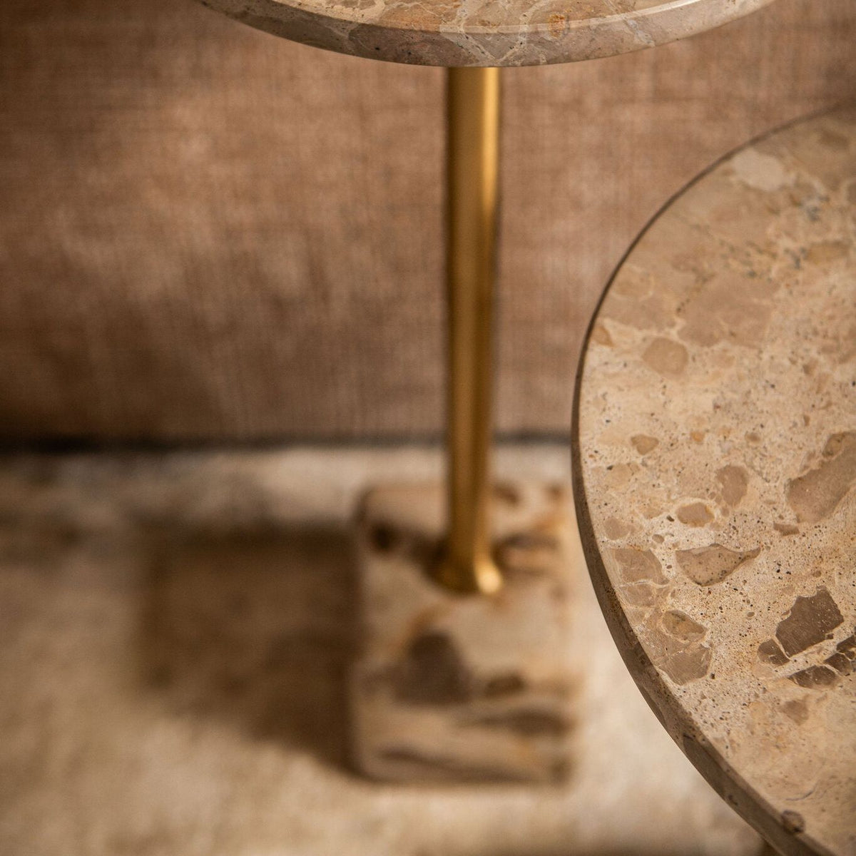 Detail van de Ebe bijzettafel van PTMD, goudkleurige stang op een blok beige marmer