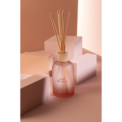 Geurstokjes Accords Essentiels Rose Rêveuse 250ml van J-Line op decoratieve blokken in een warme sfeerfoto