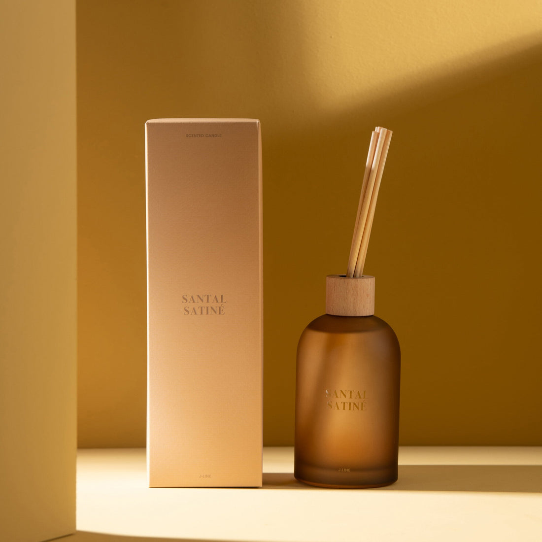 Geurstokjes Accords Essentiels Santal Satiné 250ml van J-Line met bijpassende doos in een sfeervolle gele setting